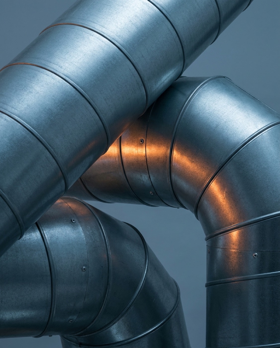 Spiral steel ductwork lit in cool blue and warm orange